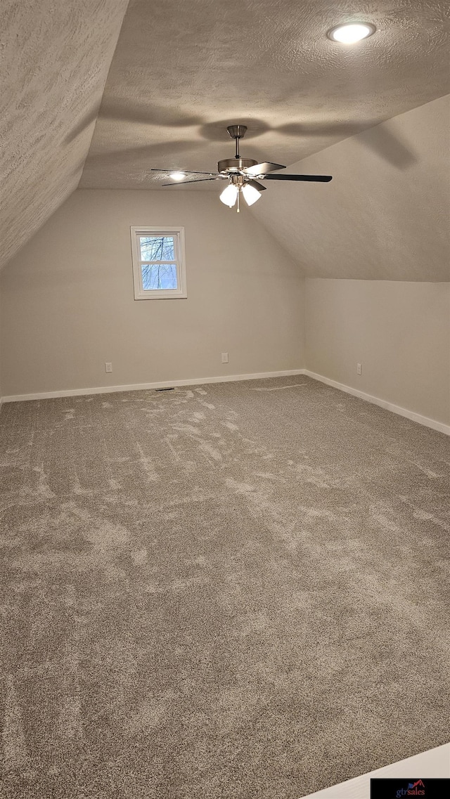 bonus room with vaulted ceiling, carpet flooring, ceiling fan, and a textured ceiling