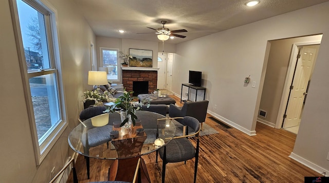 dining area featuring a fireplace, wood-type flooring, and ceiling fan