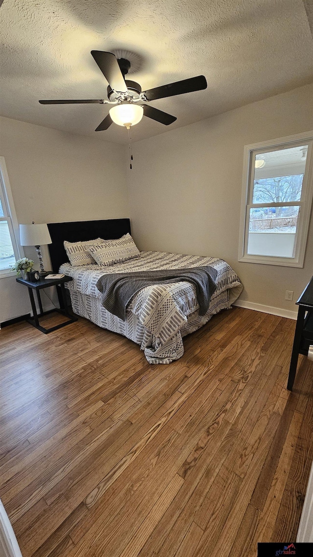 bedroom featuring hardwood / wood-style flooring, a textured ceiling, and multiple windows