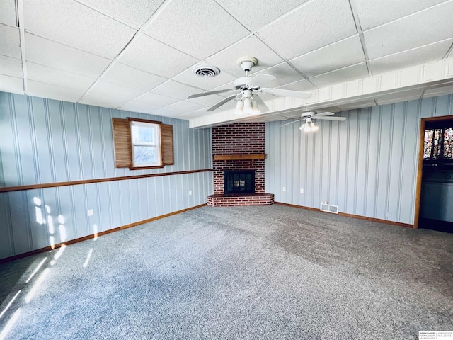 unfurnished living room featuring ceiling fan, carpet, a paneled ceiling, and a fireplace