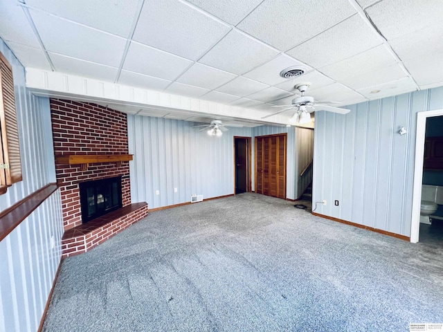 unfurnished living room featuring a fireplace, a paneled ceiling, ceiling fan, and carpet