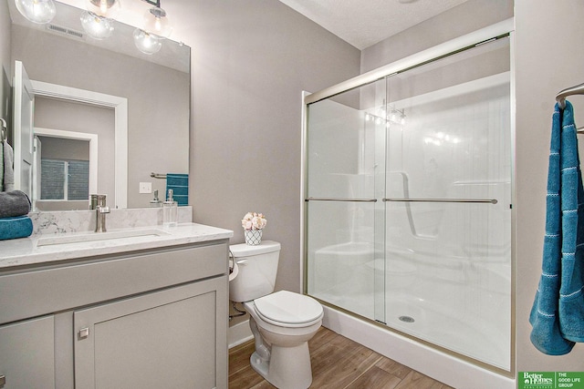 bathroom featuring walk in shower, wood-type flooring, toilet, and vanity