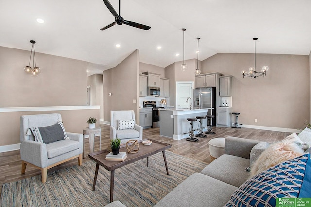 living room featuring ceiling fan with notable chandelier, hardwood / wood-style floors, and high vaulted ceiling