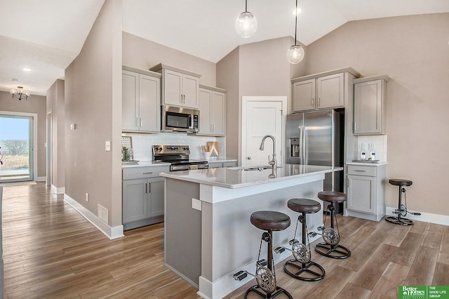 kitchen featuring sink, a center island with sink, gray cabinets, and appliances with stainless steel finishes