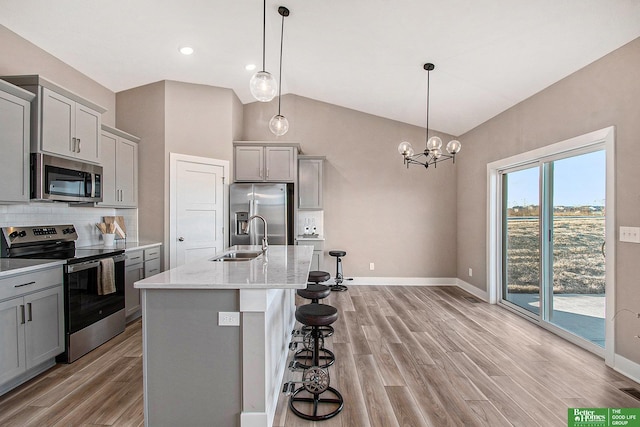 kitchen with hanging light fixtures, an island with sink, appliances with stainless steel finishes, and gray cabinetry