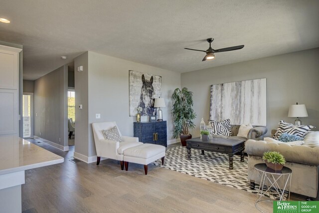 living room with a textured ceiling, wood-type flooring, and ceiling fan