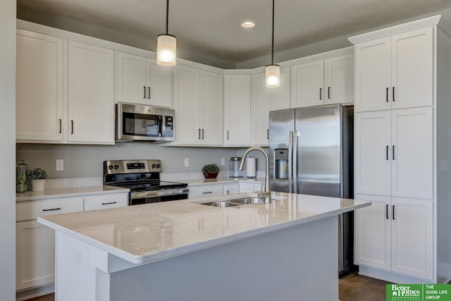 kitchen with stainless steel appliances, an island with sink, hanging light fixtures, and white cabinets