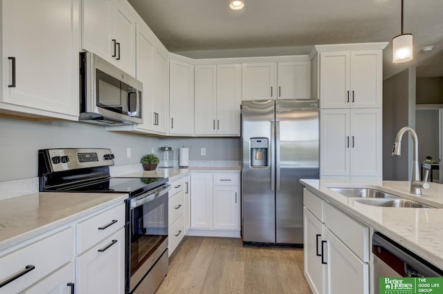 kitchen featuring sink, white cabinetry, light stone counters, hanging light fixtures, and appliances with stainless steel finishes