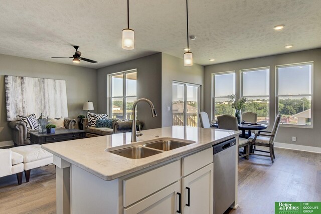 kitchen with decorative light fixtures, dishwasher, an island with sink, sink, and white cabinets