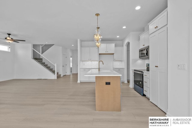 kitchen featuring pendant lighting, sink, a kitchen island with sink, white cabinetry, and stainless steel appliances