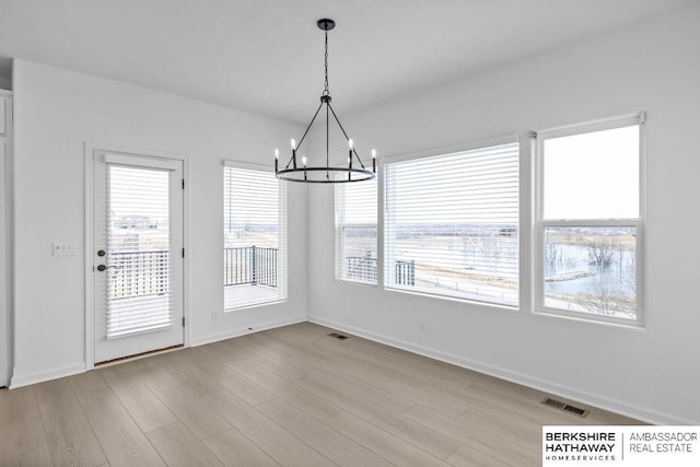 unfurnished dining area with an inviting chandelier and light hardwood / wood-style flooring