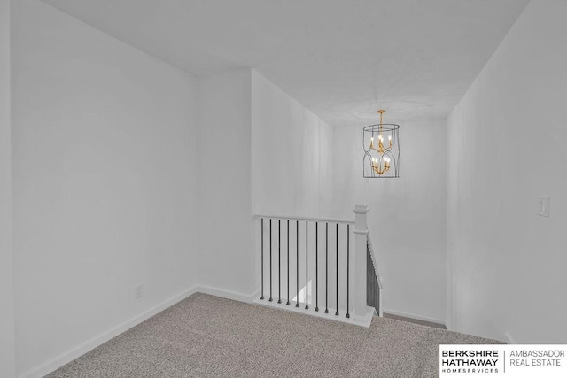 spare room featuring an inviting chandelier and carpet flooring