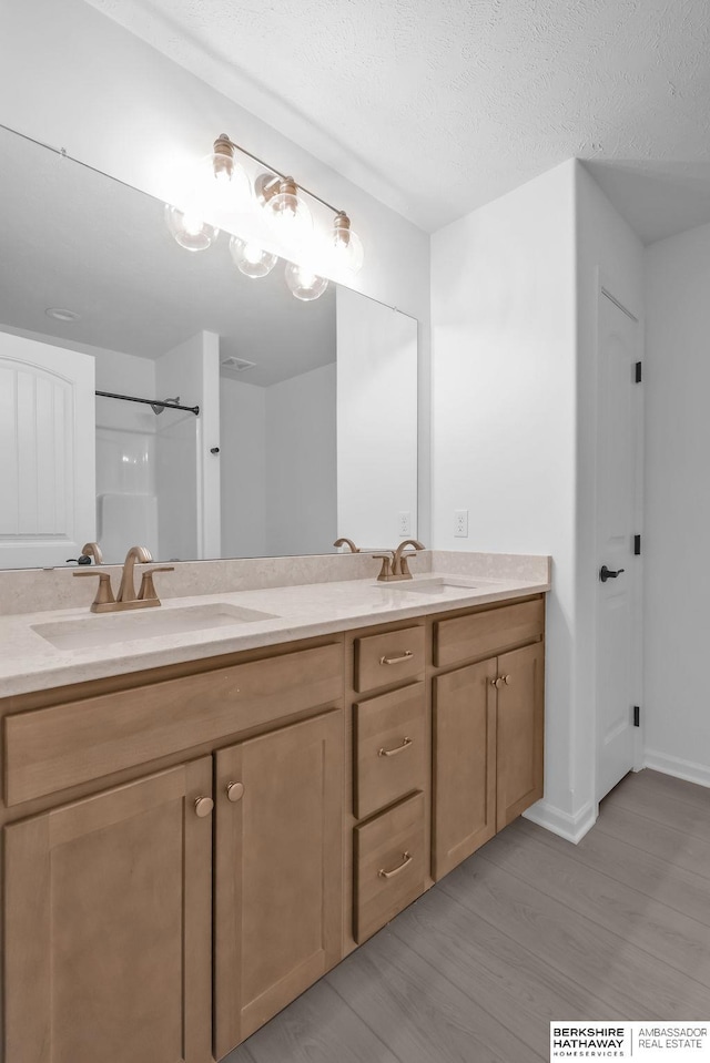 bathroom with walk in shower, vanity, hardwood / wood-style floors, and a textured ceiling