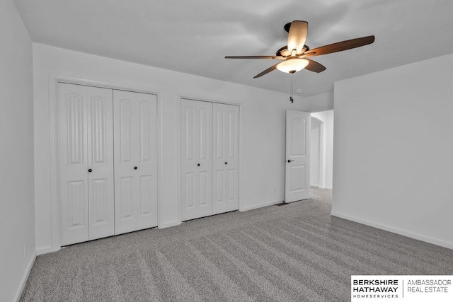 unfurnished bedroom with multiple closets, light colored carpet, and ceiling fan