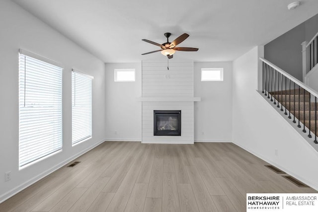 unfurnished living room featuring ceiling fan, a fireplace, and light hardwood / wood-style floors