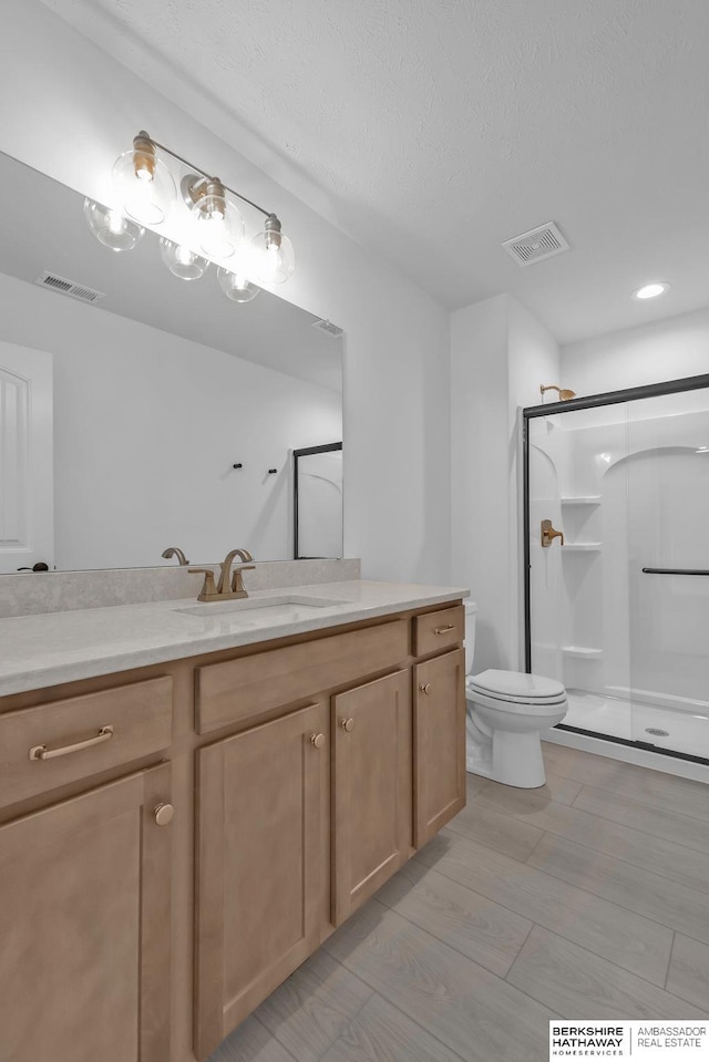 bathroom featuring vanity, toilet, and a shower with door