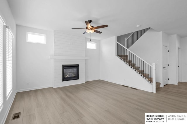 unfurnished living room with a fireplace, a wealth of natural light, and light hardwood / wood-style floors