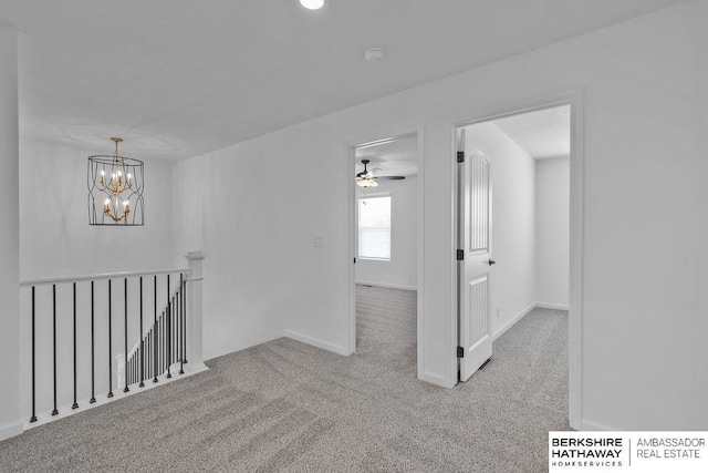 carpeted spare room with ceiling fan with notable chandelier