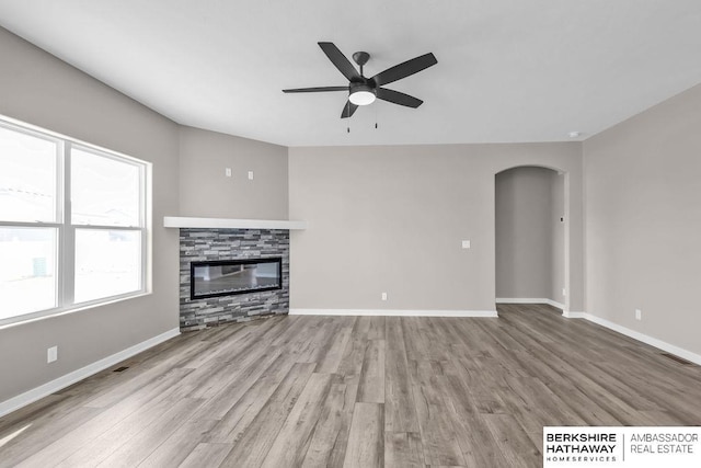 unfurnished living room featuring ceiling fan, light wood-type flooring, and a fireplace