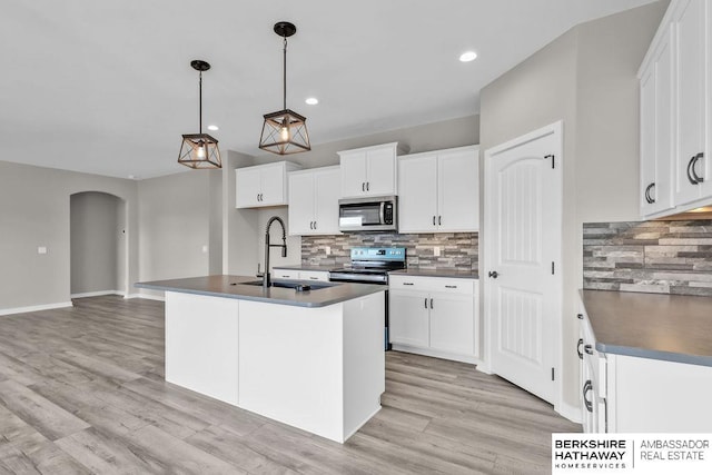 kitchen featuring white cabinetry, an island with sink, sink, hanging light fixtures, and stainless steel appliances