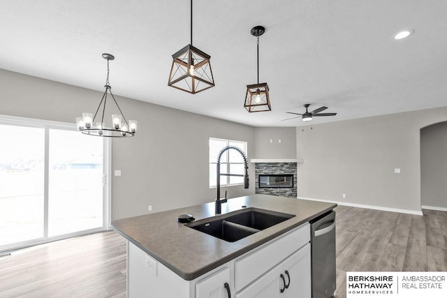 kitchen featuring sink, decorative light fixtures, dishwasher, a fireplace, and white cabinets