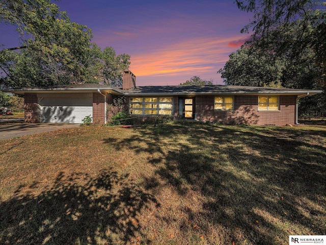 ranch-style home featuring a garage and a lawn