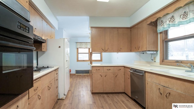 kitchen featuring light brown cabinetry, extractor fan, sink, light hardwood / wood-style flooring, and appliances with stainless steel finishes