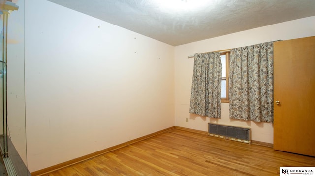 unfurnished room with wood-type flooring and a textured ceiling