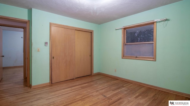 unfurnished bedroom with light hardwood / wood-style floors, a closet, and a textured ceiling