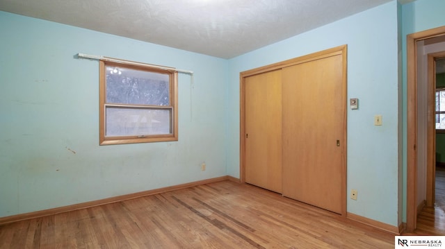 unfurnished bedroom featuring light hardwood / wood-style flooring, a closet, and a textured ceiling