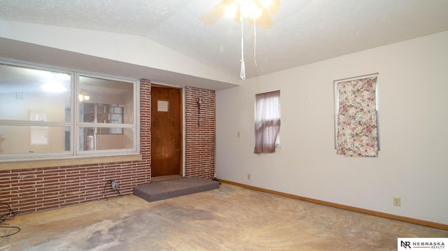 spare room with brick wall, lofted ceiling, and a textured ceiling