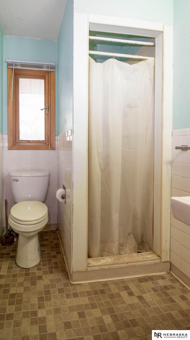 bathroom featuring tile walls, curtained shower, and toilet