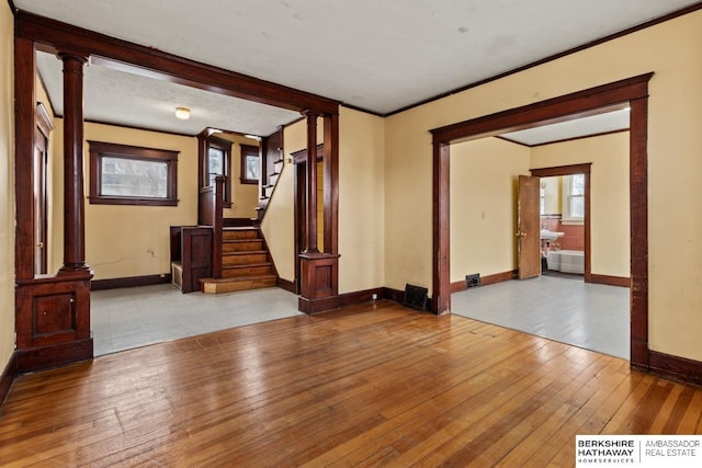 empty room featuring ornamental molding, light hardwood / wood-style flooring, and ornate columns