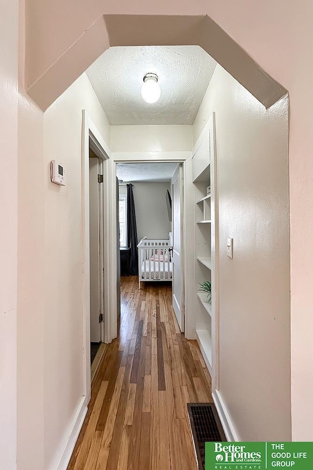 corridor featuring hardwood / wood-style floors and a textured ceiling