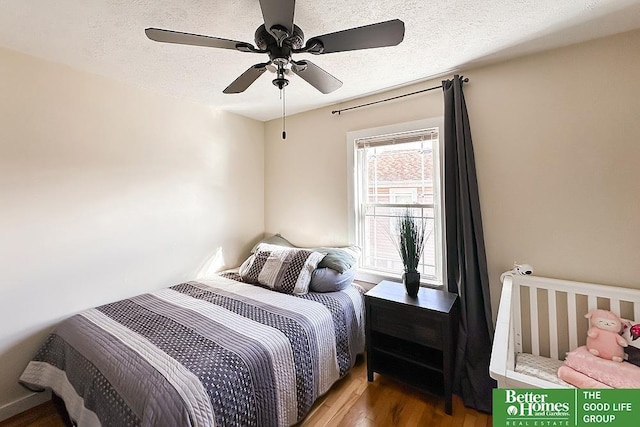 bedroom with ceiling fan, wood-type flooring, and a textured ceiling