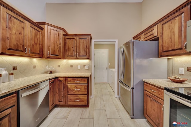 kitchen featuring stainless steel appliances, backsplash, and light stone counters