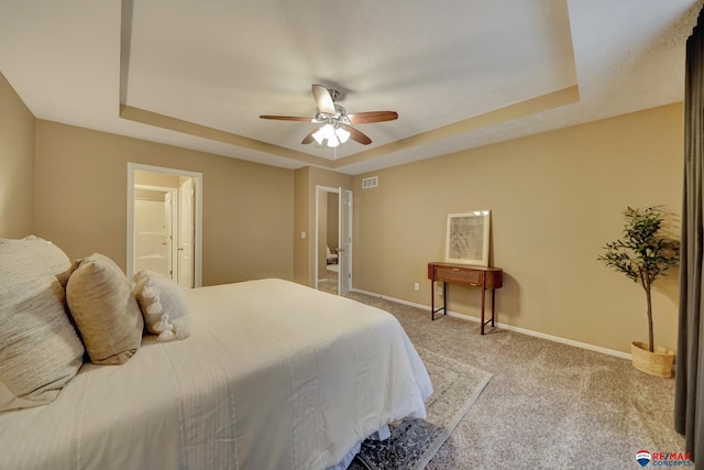 bedroom with connected bathroom, a raised ceiling, ceiling fan, and carpet