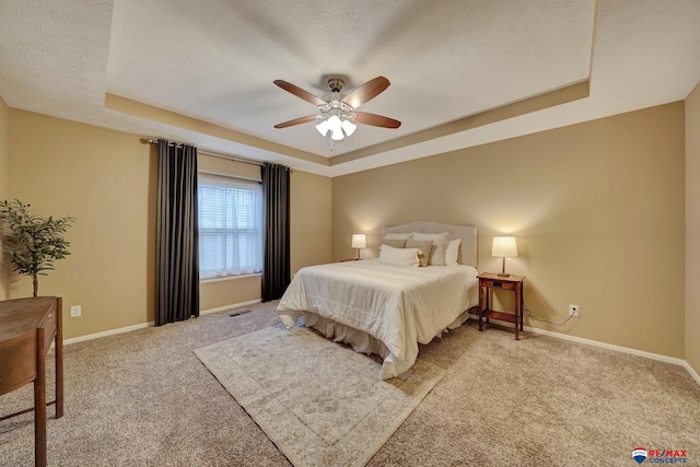 bedroom featuring ceiling fan, a tray ceiling, carpet, and a textured ceiling