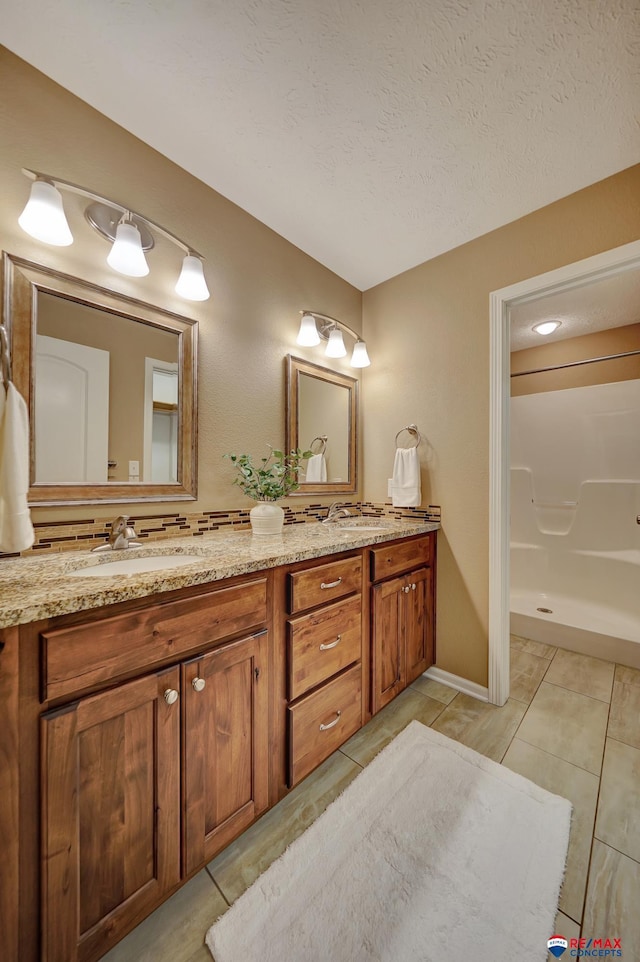 bathroom featuring vanity, tile patterned flooring, a textured ceiling, and a shower