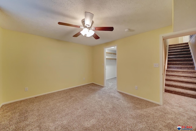 carpeted spare room with ceiling fan and a textured ceiling