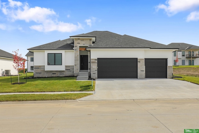 prairie-style home with a garage, a front yard, and central air condition unit