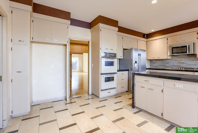 kitchen with white cabinets, appliances with stainless steel finishes, and backsplash