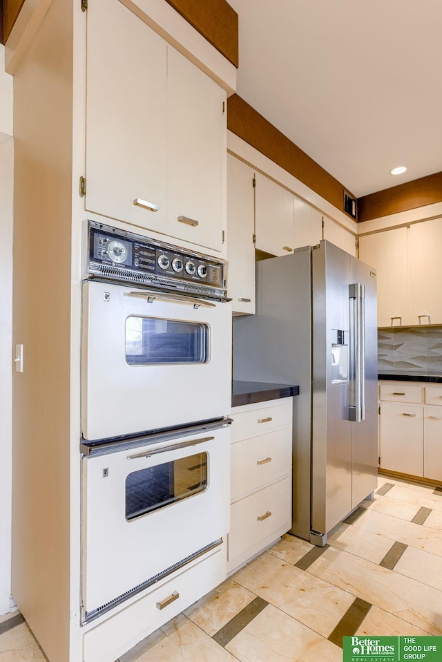 kitchen featuring white cabinetry, high end refrigerator, and white double oven