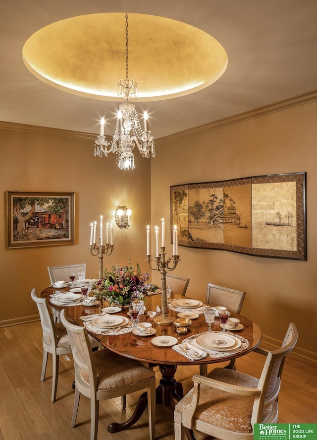 dining space with crown molding, wood-type flooring, and a raised ceiling