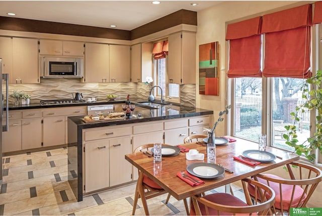 kitchen featuring sink, appliances with stainless steel finishes, kitchen peninsula, cream cabinets, and decorative backsplash