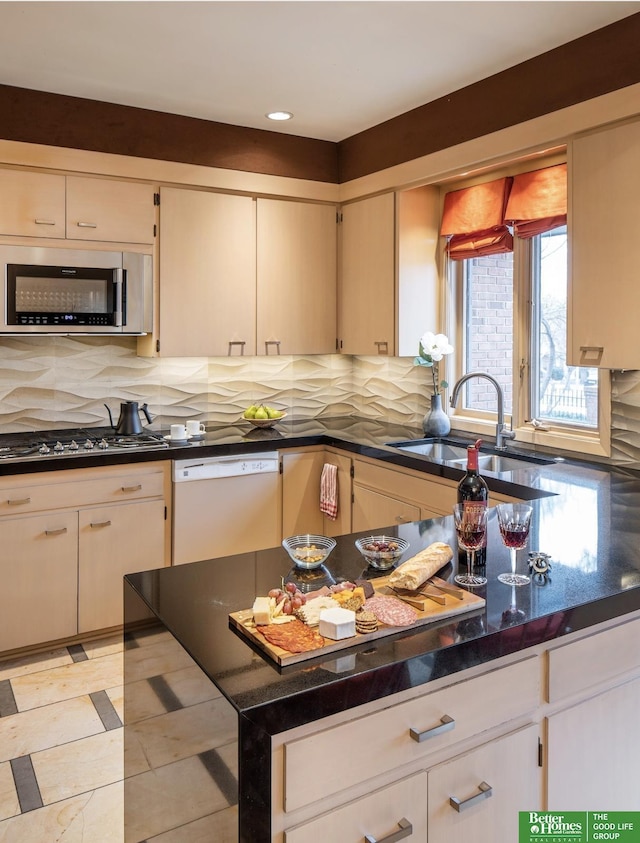 kitchen featuring stainless steel appliances, sink, dark stone counters, and decorative backsplash