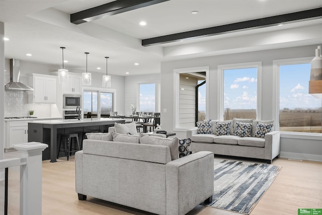 living room with beamed ceiling and light wood-type flooring