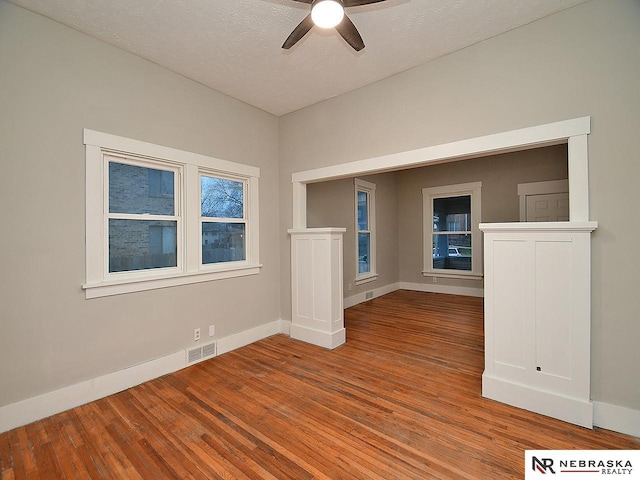 empty room with hardwood / wood-style flooring, ceiling fan, and a textured ceiling