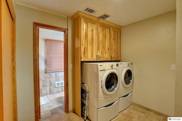 clothes washing area featuring cabinets and washing machine and clothes dryer