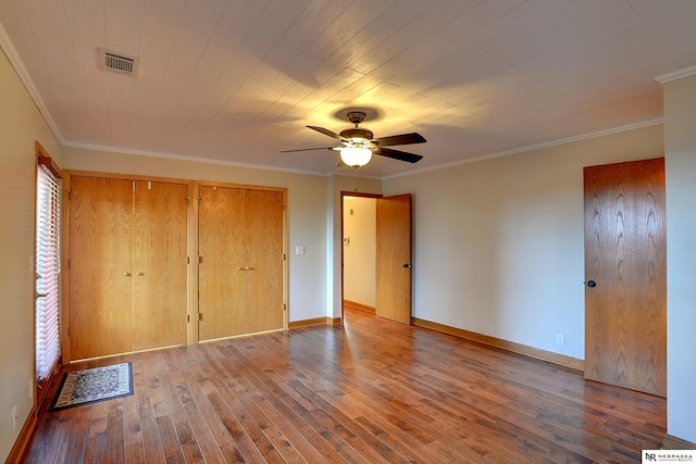 unfurnished bedroom featuring ornamental molding, two closets, hardwood / wood-style floors, and ceiling fan